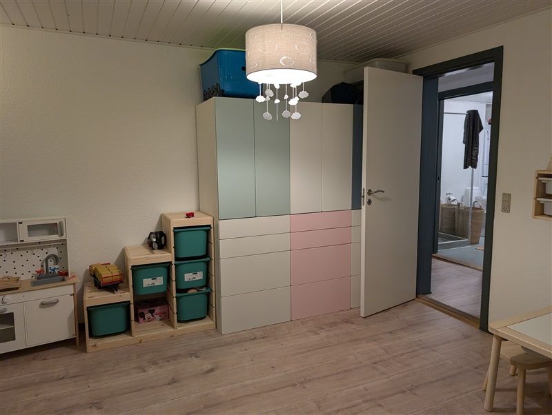 Et farverig og moderne børneværelse med en stor højskab og en køkkenhylde med mikroovn og tegnebord