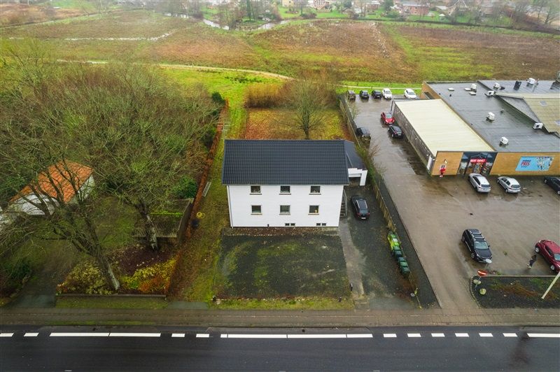 En bygning med garage og parkeringsplads i Vejlevej 14, Sønder Omme med omgivende grønne områder og skov