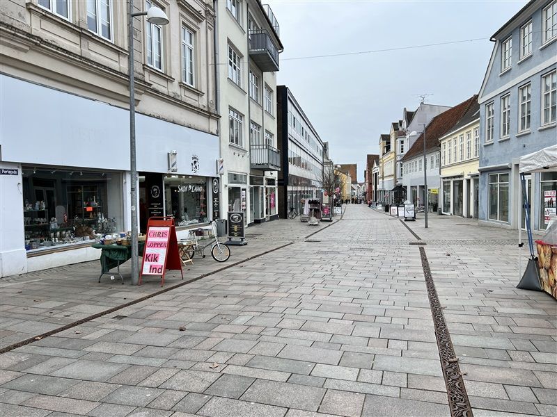 Gade med tomme gadefliser, et schild med navnet Chris Lopper og en cykel parkeret ved siden af
