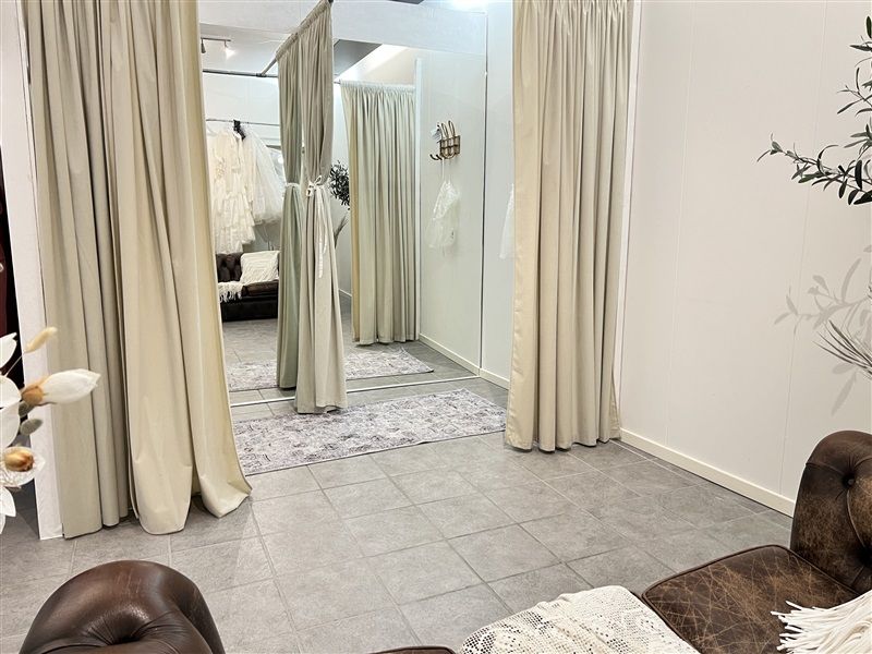 Lejlighed med garderobe, spejl og tæpper samt brun sofa og løvfletede plante