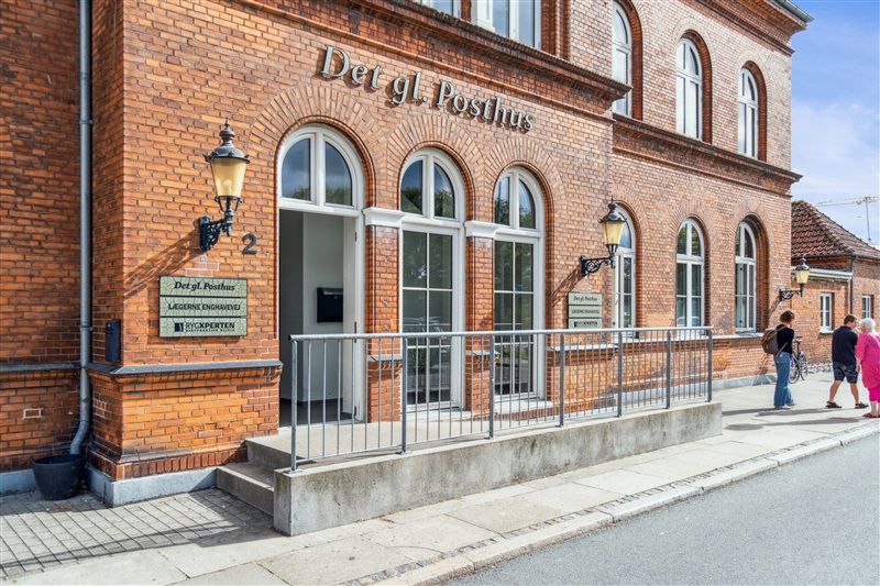 Det gl. Posthus i Nyborg med røde mursten og glasvinduer, lægner og rygsække og kvinder i pink og mænd i sort og hvid