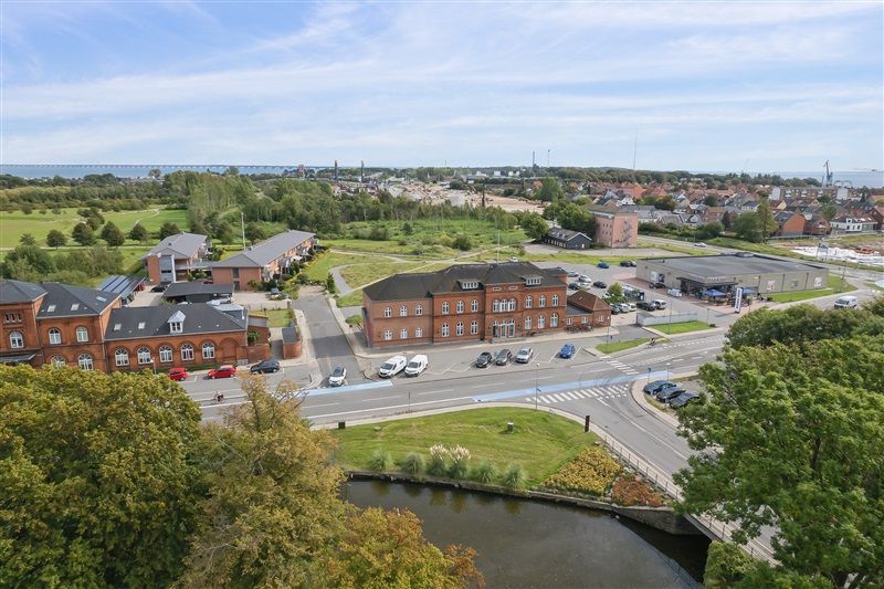 Ejerskabet erhvervslokaler i Nyborg. Bygninger med parkeringspladser og grønne områder. Gågade med biler og grønne træer.