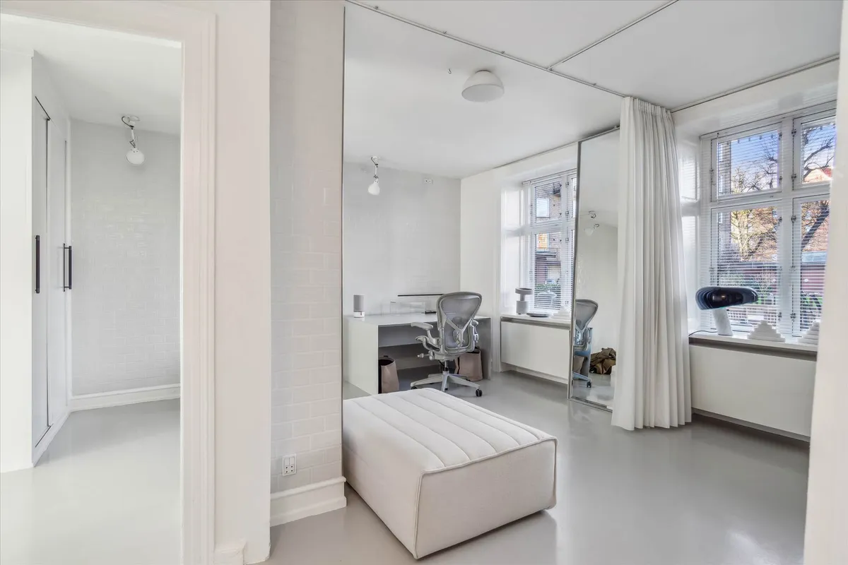 Hjørnekontor med højt spejl og store vinduer i moderne interiør med hvidt og gråt gulv og hvide vægge