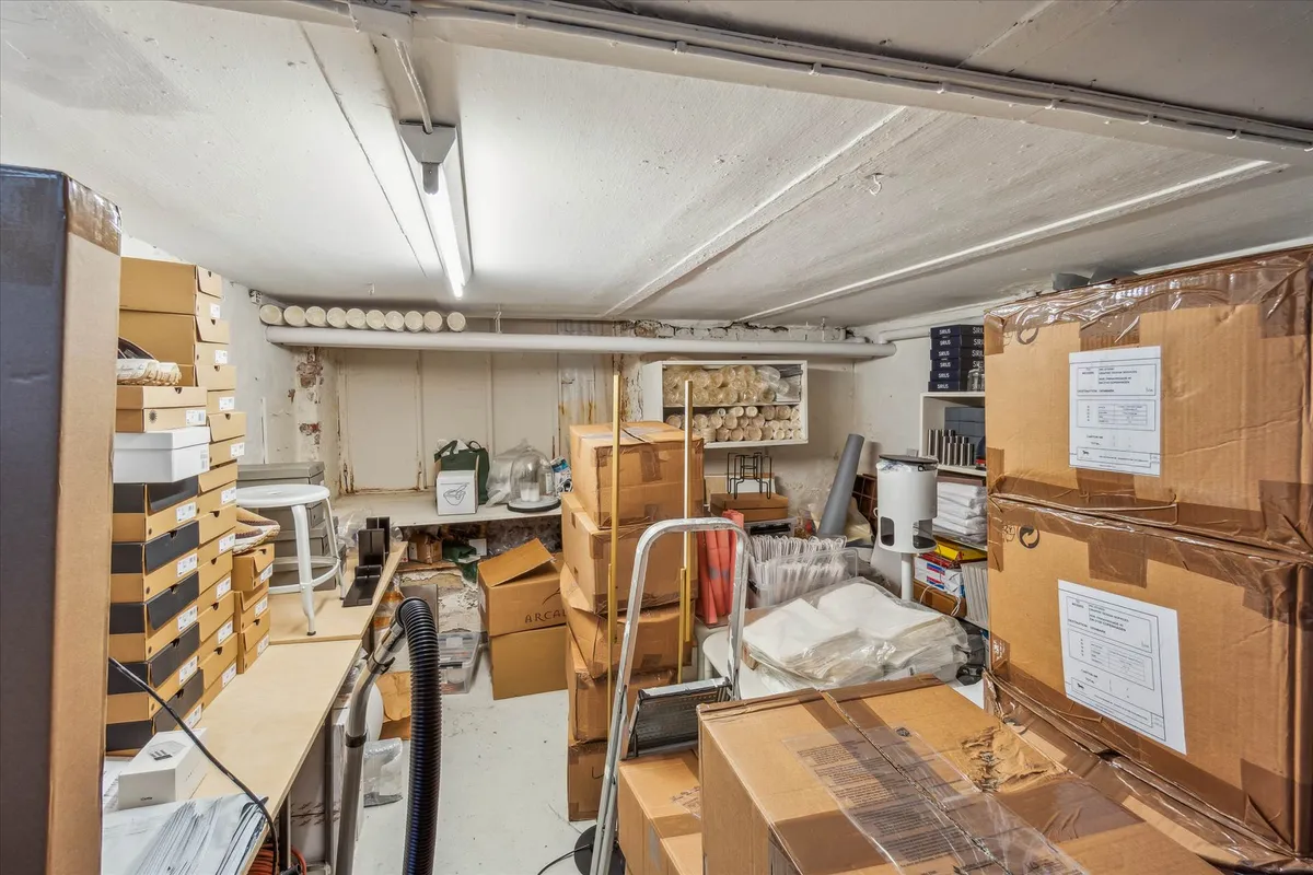 Lager med flere kasser og pakker, gamle stol, udstyr og højrekantet regnskab.