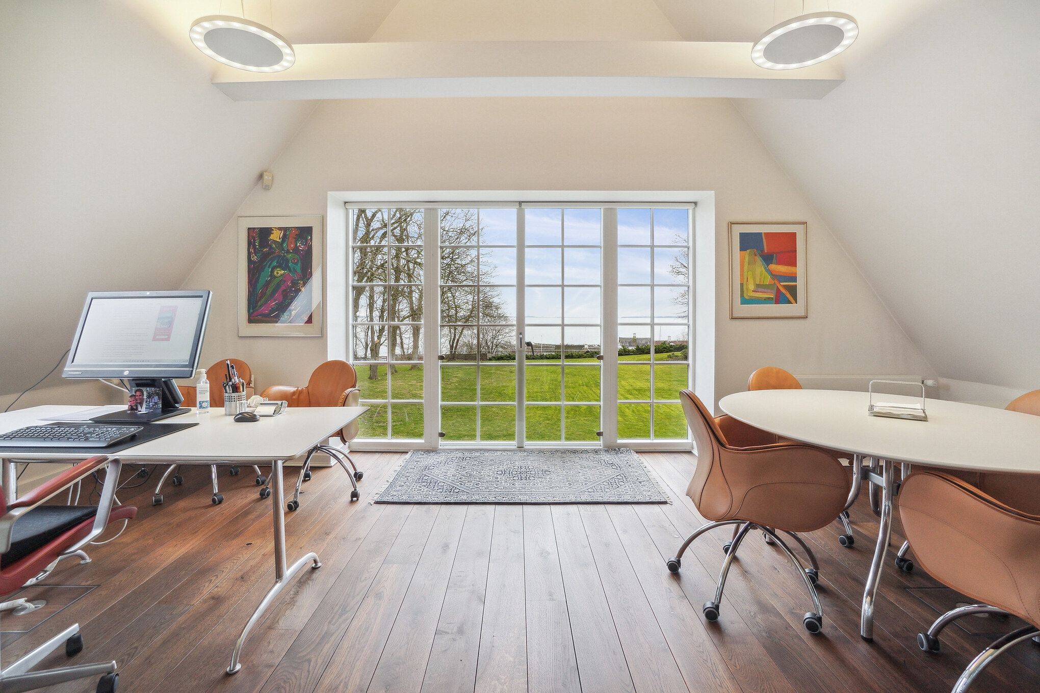 Kontor med skriveborde, hvor der er monitor, tastatur og mus samt flere stolpe stol ved skrivebordene