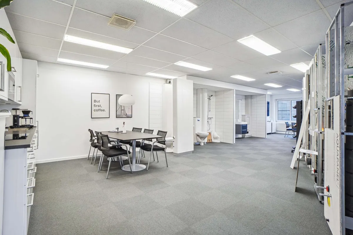 Værelse med lysegul gulvbelægning, hvide vægge, højt til loftet, flere møbler og en tekst på væggen