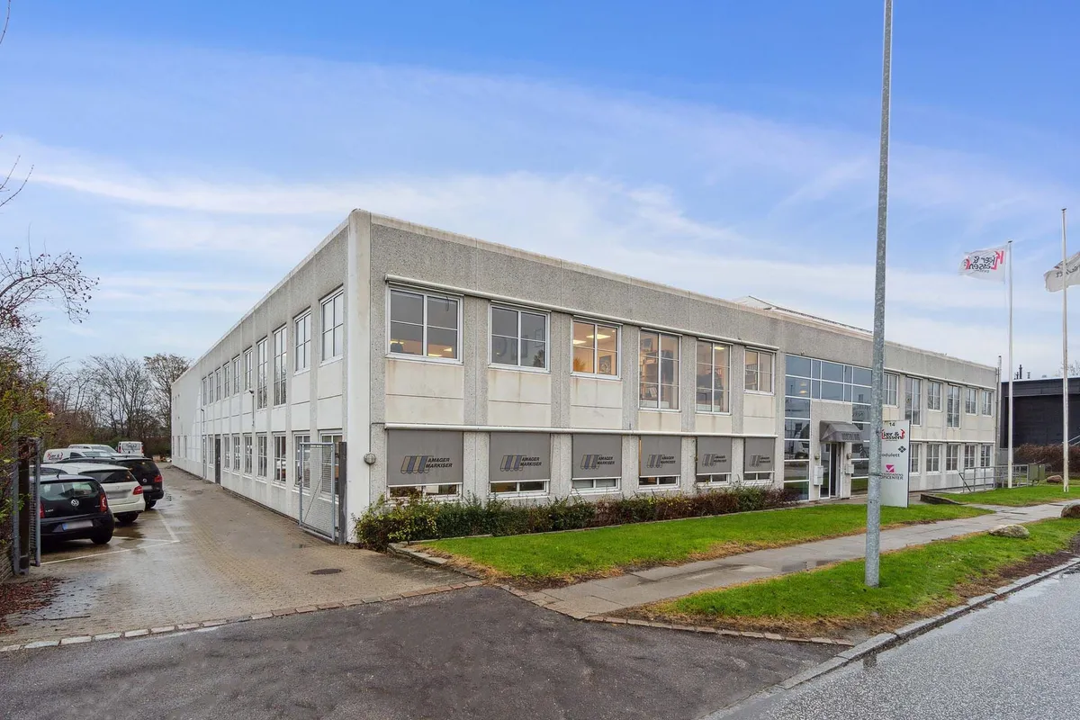 Moderne erhvervsbygning med parkeringsplads og kontorer i område med flere virksomheder