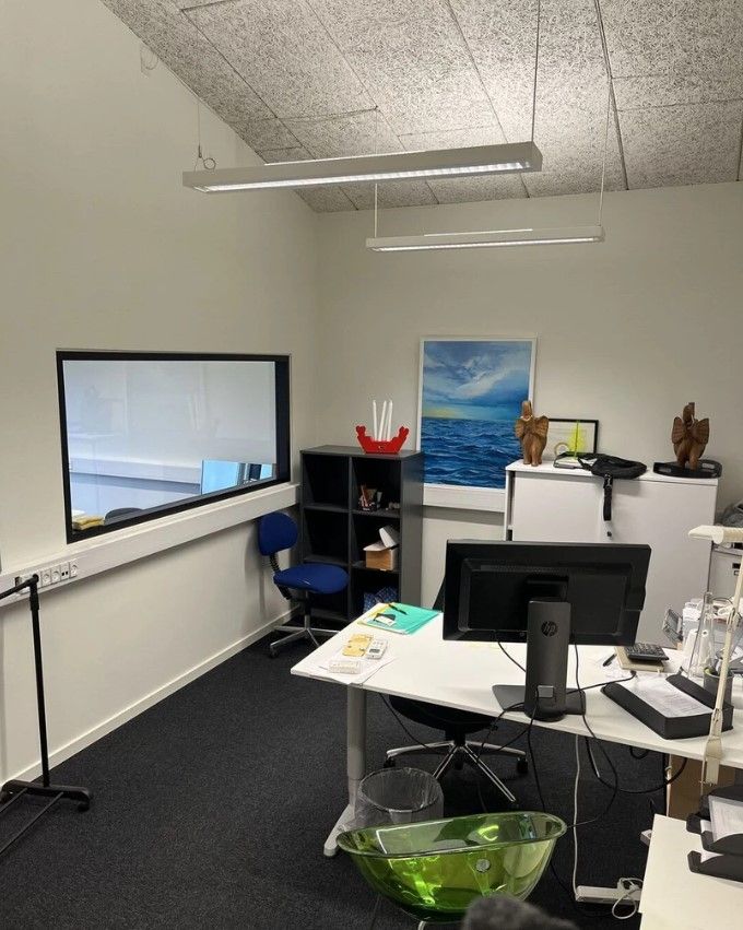 Kontorlokaler med lyse loftsbelægninger og en skrivebord med en HP-computer og en skrivemaskine