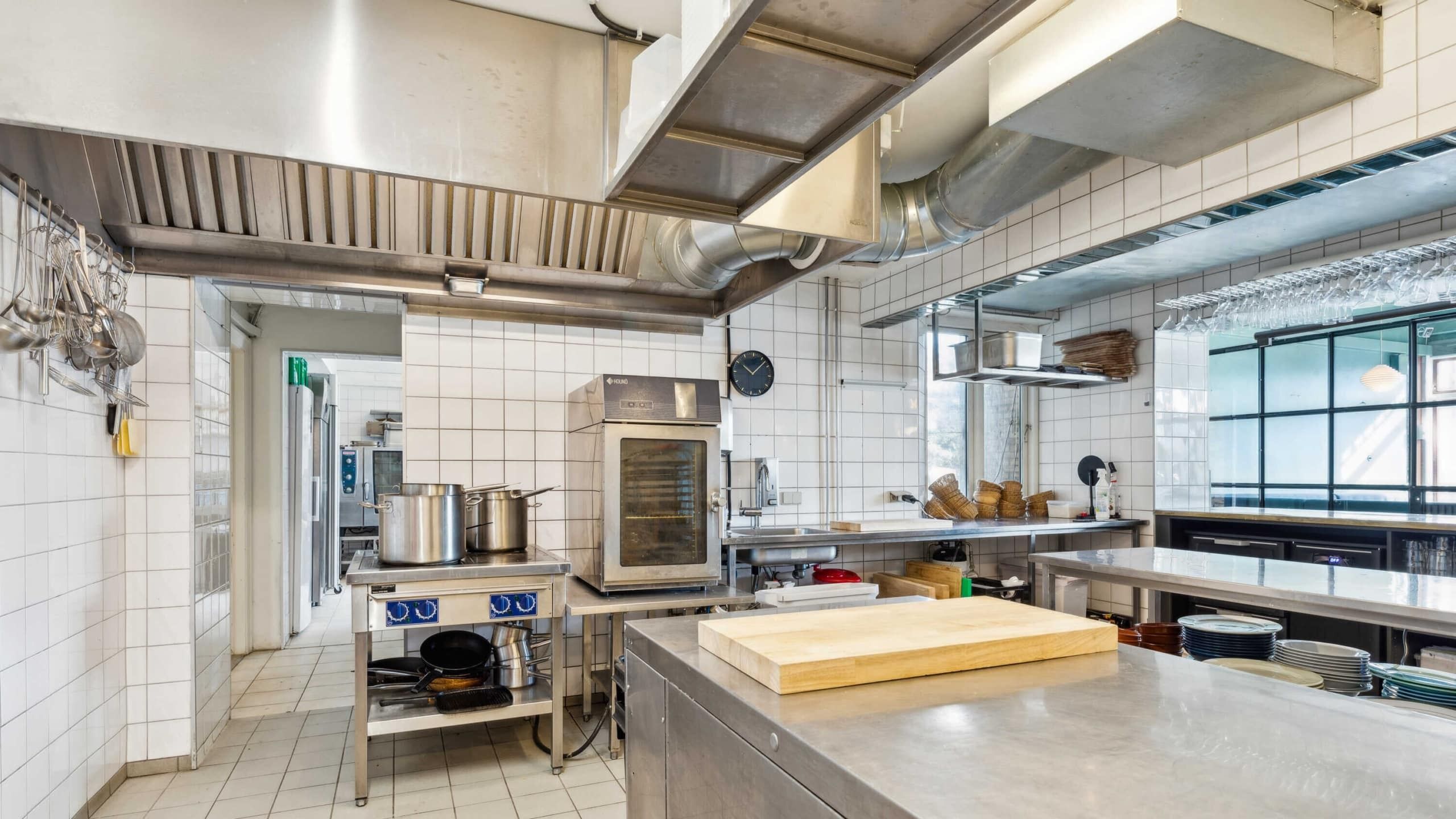 En ren og velorganiseret kommerciel køkken med en stor ovn og en slibeskive, der er placeret på en metalbord