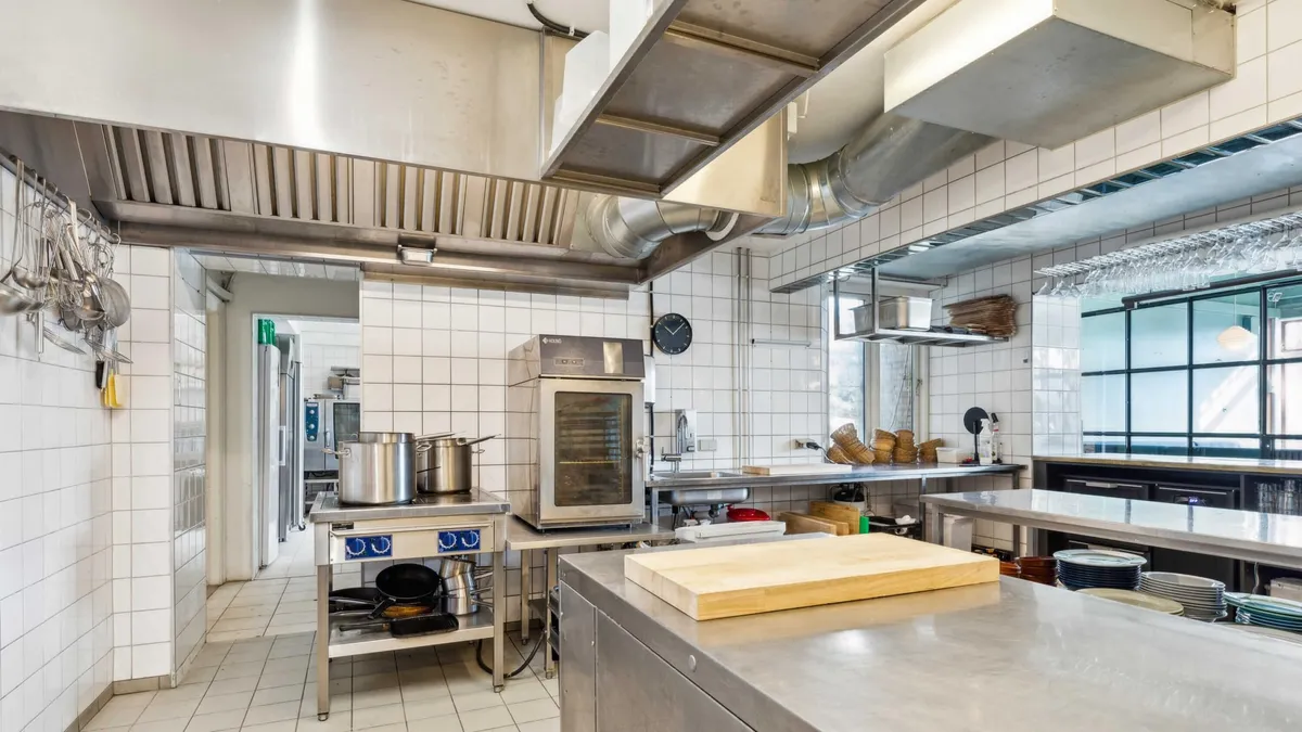 En ren og velorganiseret kommerciel køkken med en stor ovn og en slibeskive, der er placeret på en metalbord