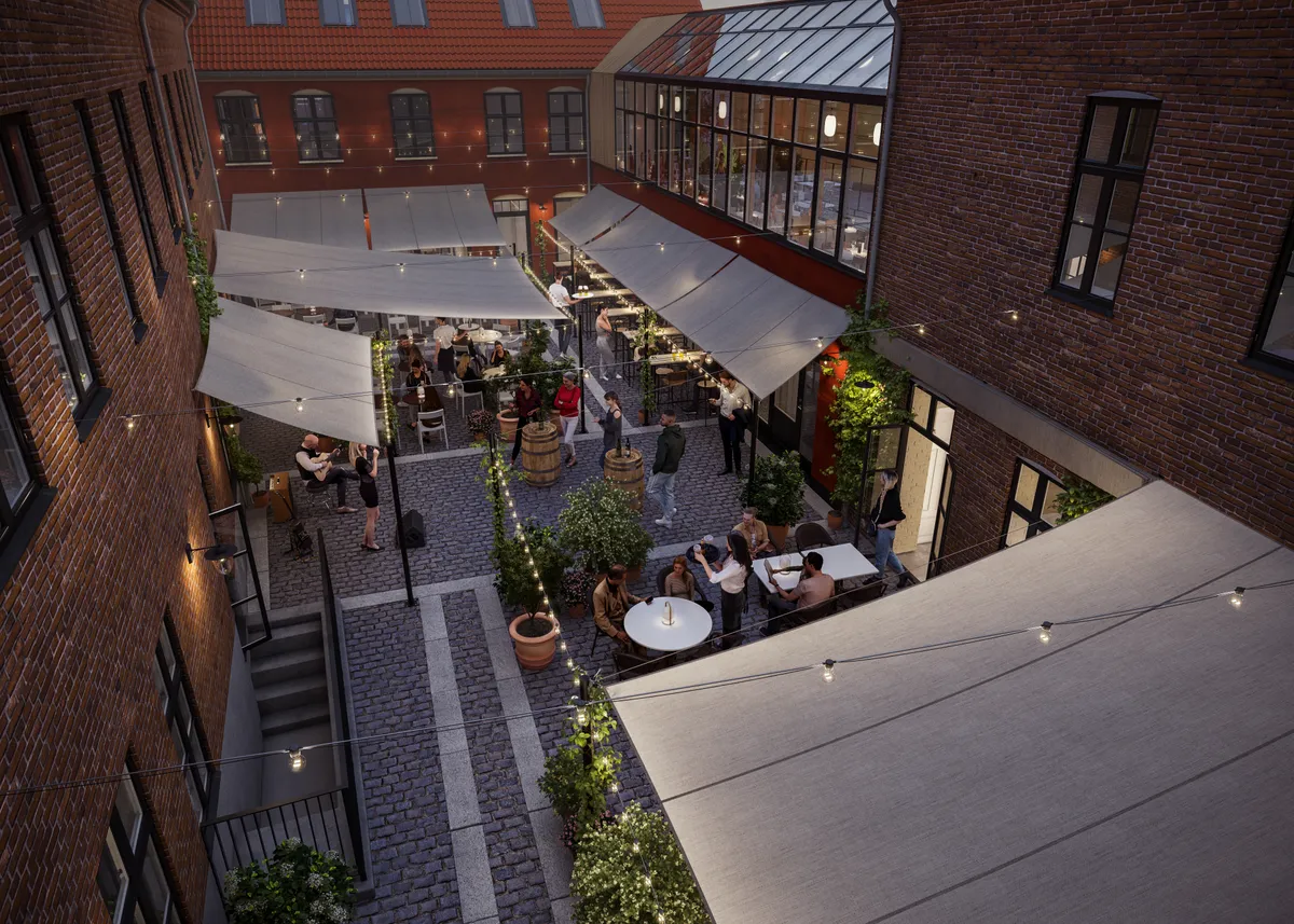 En udeservering med bord og stole, lysekroner og terrassedækning samt gæster, der nyder deres ophold