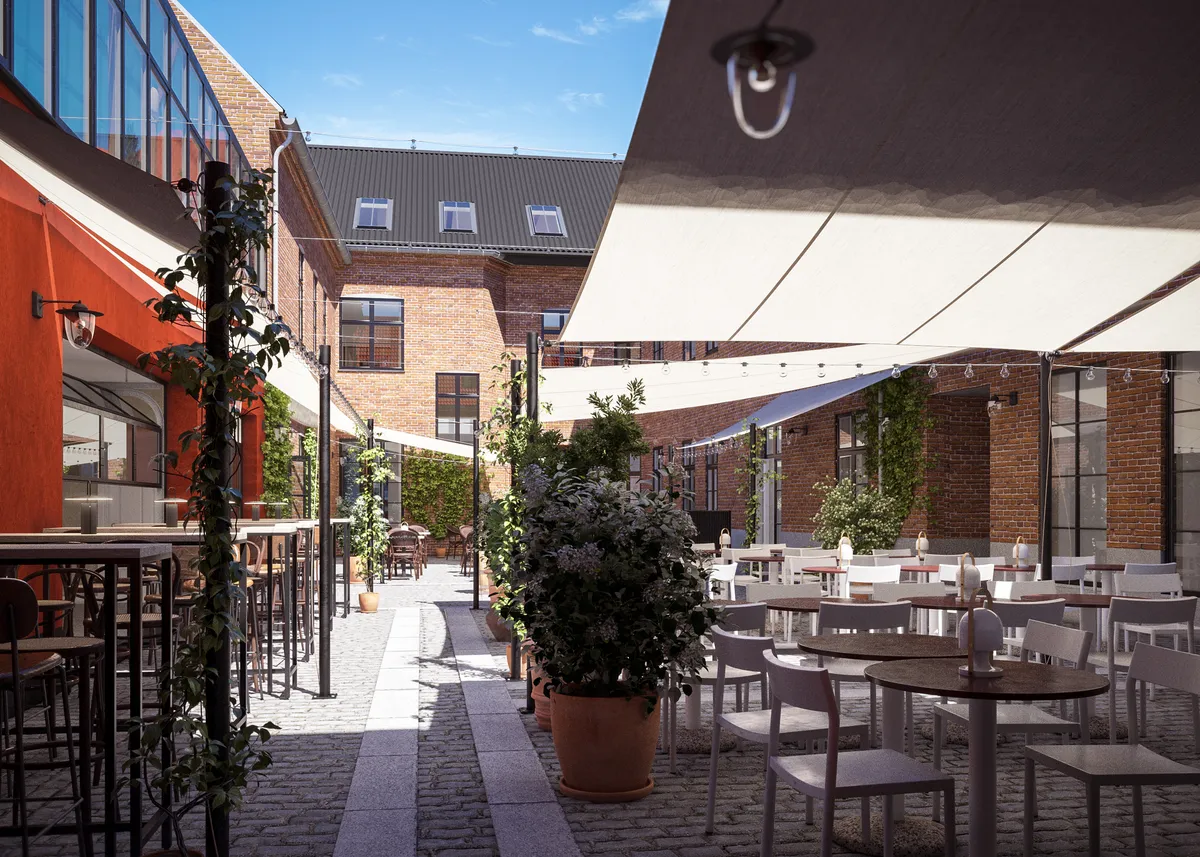 En hyggelig gårdhave med lyse træborde og stole samt små planter og udendørs belysning