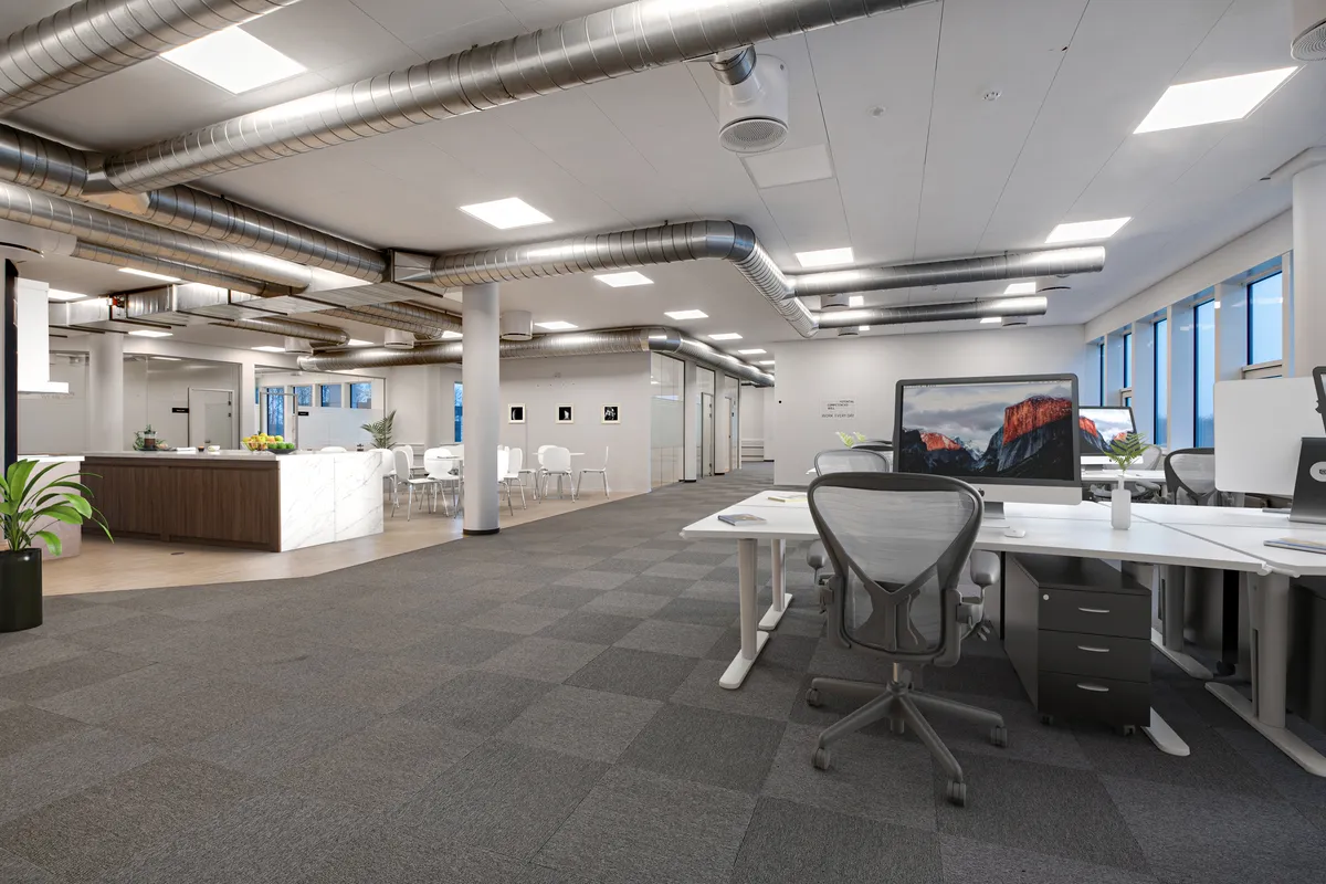 En moderne kontor med hvide vægge, glasruder og store vinduer med udsigt til byen. Kontoret er udstyret med kontormøbler og