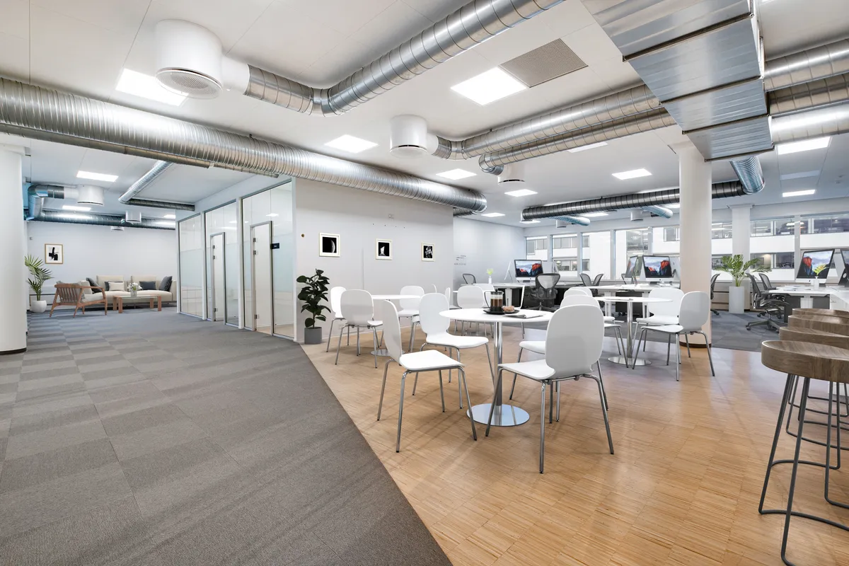 Moderne kontor med trægulve, hvide borde og stole, plante og computere