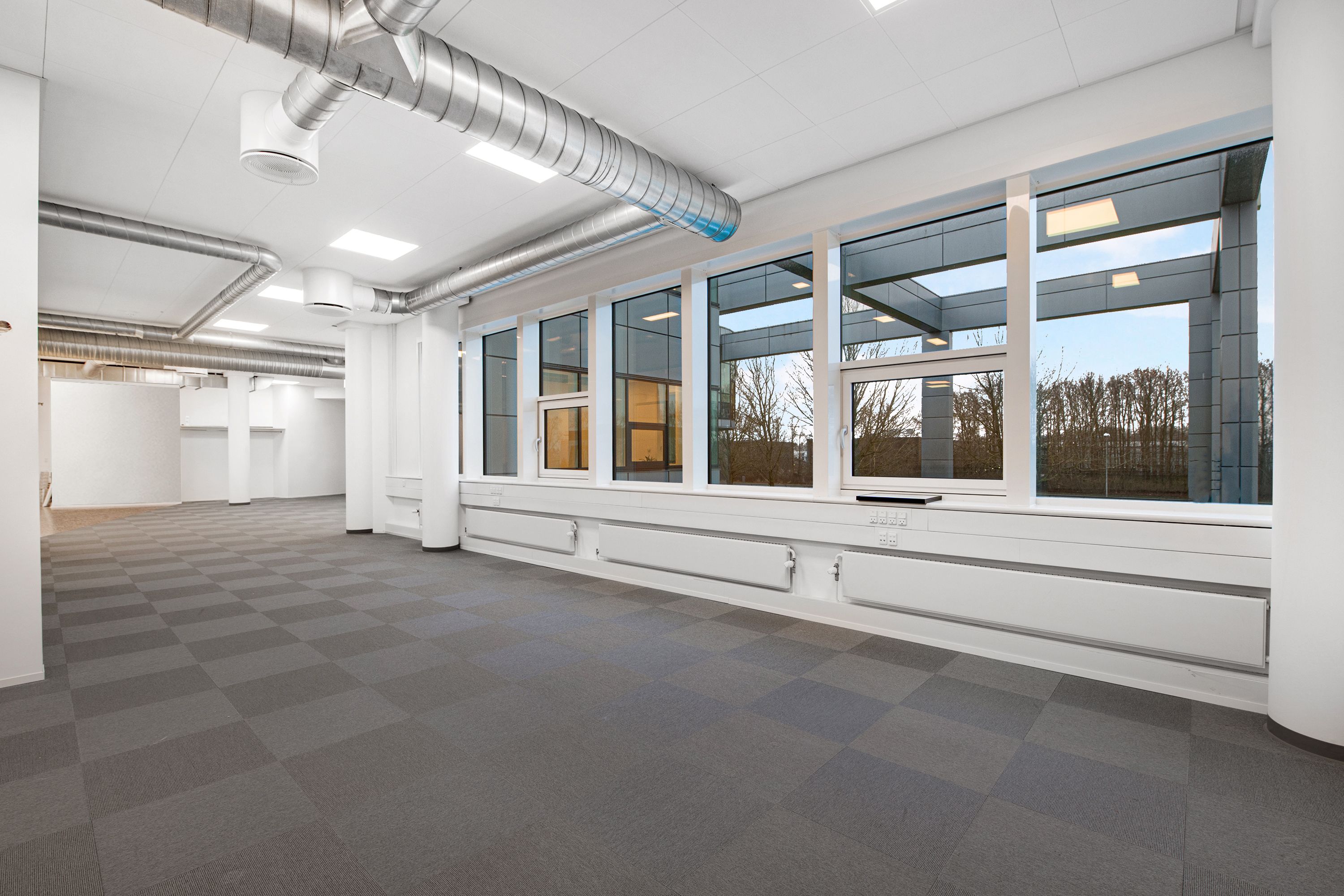 Et nyt og luksuriøst kontorrum med glasvinduer og indbygget klimaanlæg. Værelset er smagfuldt indrettet med lysegrå