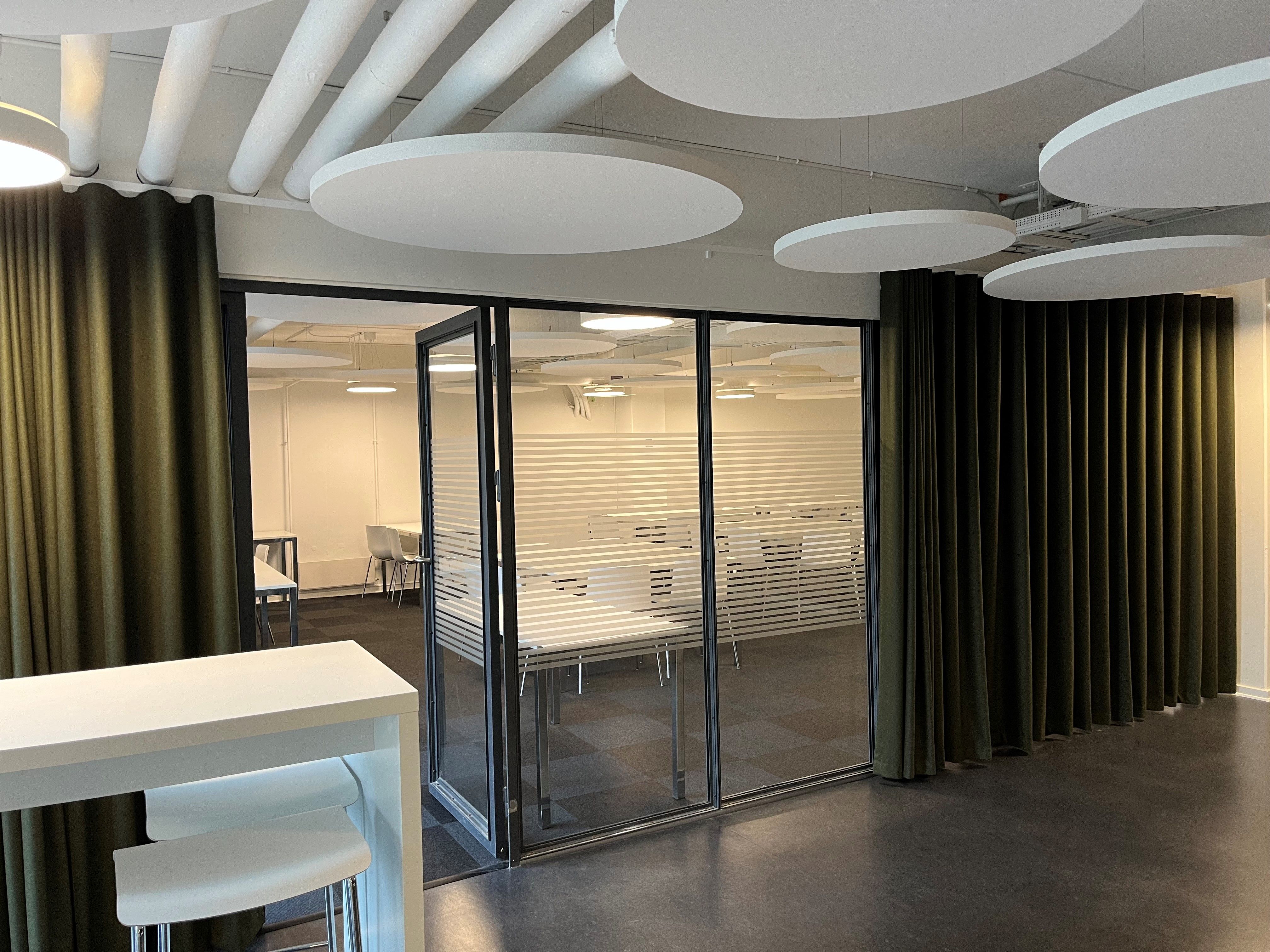 Kontorrum med højt loft, runde lysekroner, mørke gardiner og glasdøre
