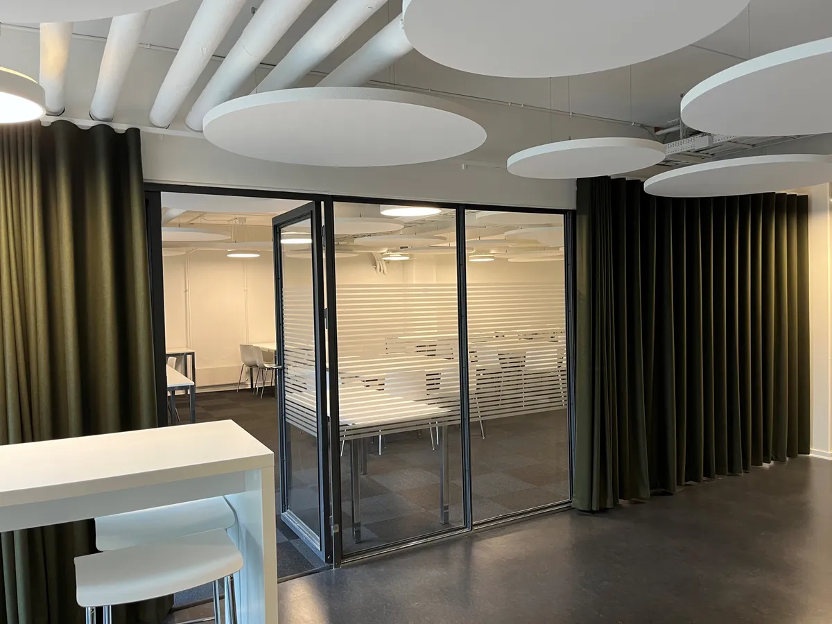 Kontorrum med højt loft, runde lysekroner, mørke gardiner og glasdøre