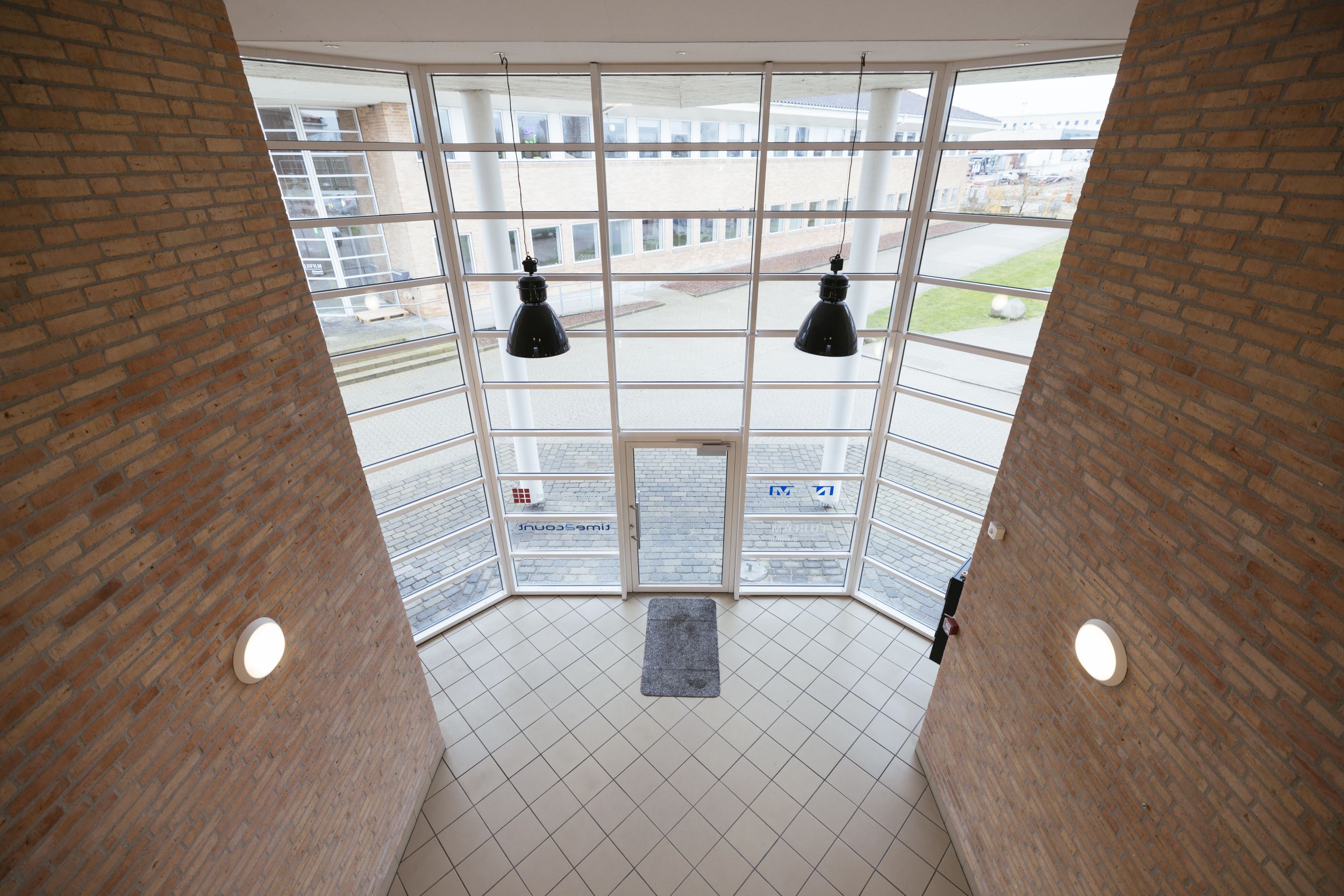 Moderne kontor med glasvinduer og lysekroner, hoveddør og tæppe, gulvtæppe og væglamper, udendørs græsplæne og