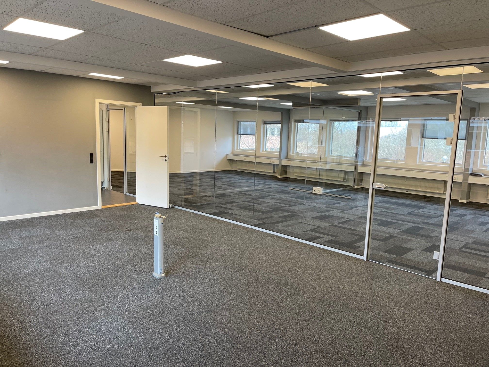 Store kontor med højt loft og glasvægge og gulvbelægning i lyse farver