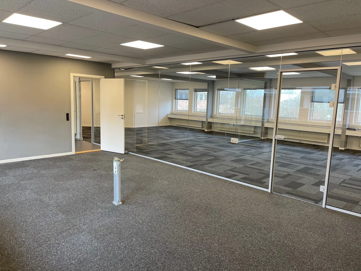 Store kontor med højt loft og glasvægge og gulvbelægning i lyse farver