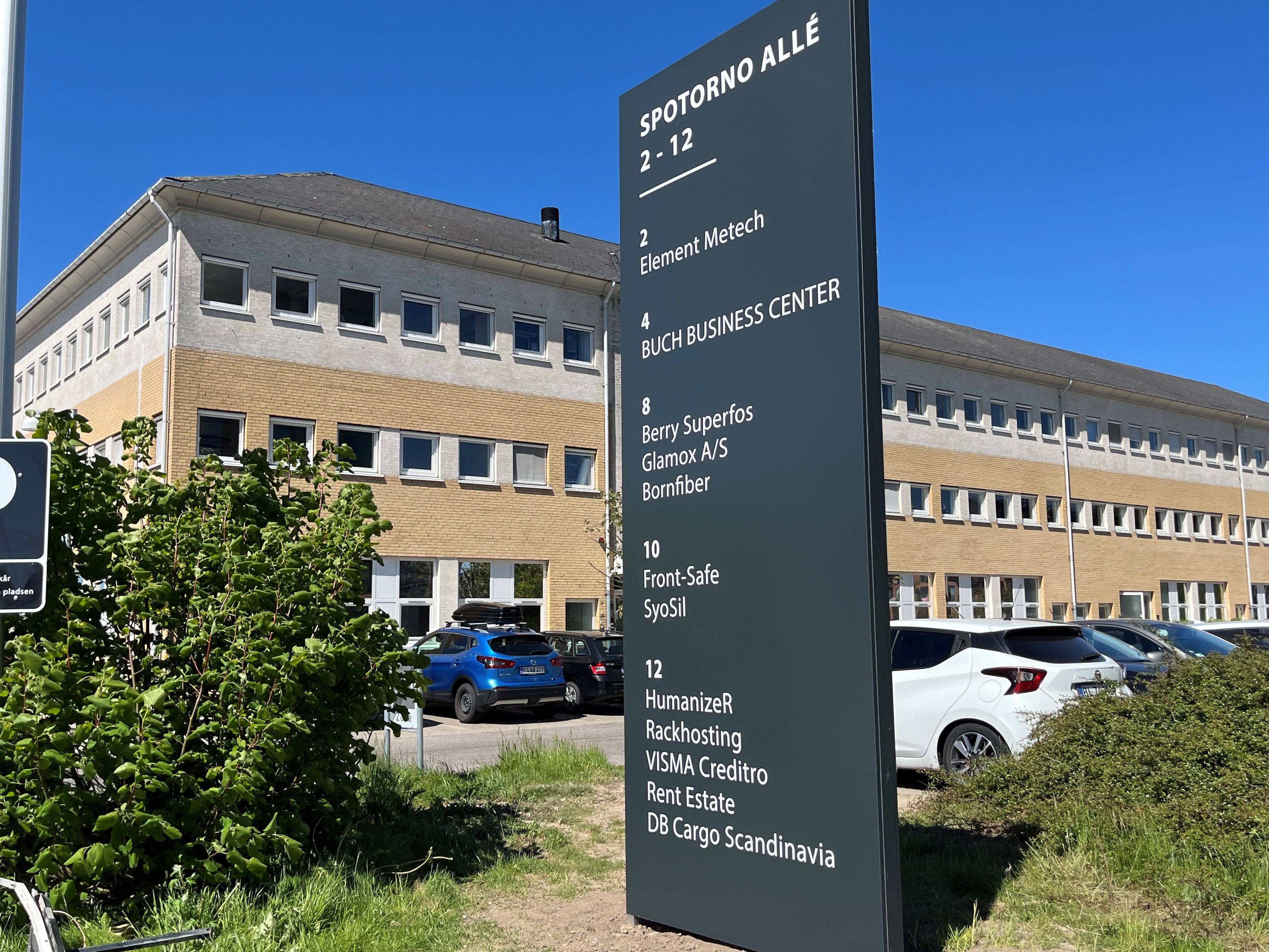 Butikspark med flere firmaer som Element Metech og Front-Safe. Parkerede biler og grønne planter.