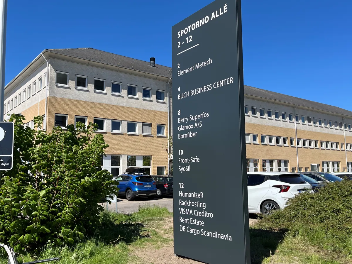 Butikspark med flere firmaer som Element Metech og Front-Safe. Parkerede biler og grønne planter.