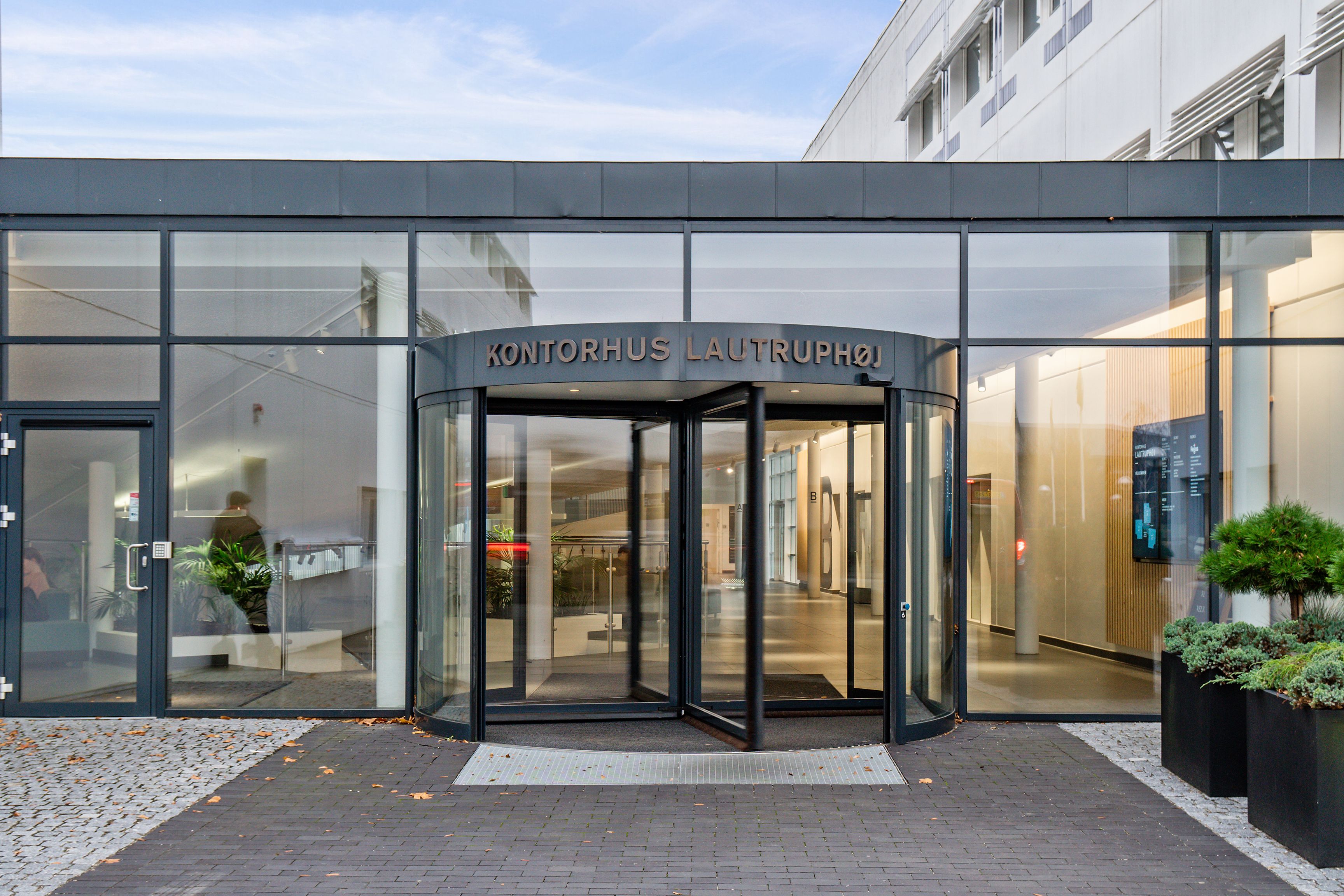 Lejlighedsbygning med glashuset indgangsparti og automatiske drejedøre med teksten Kontorhus Lautruphoj