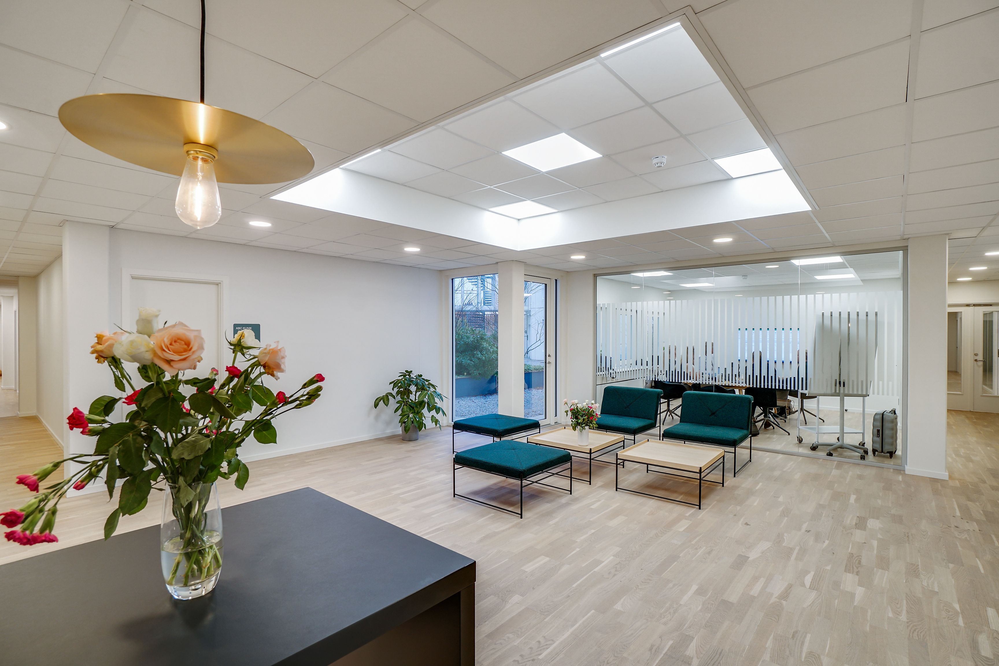 Lejlighed med møbleret stue, tre smukke grønne stolene og en lysegul loftslampe