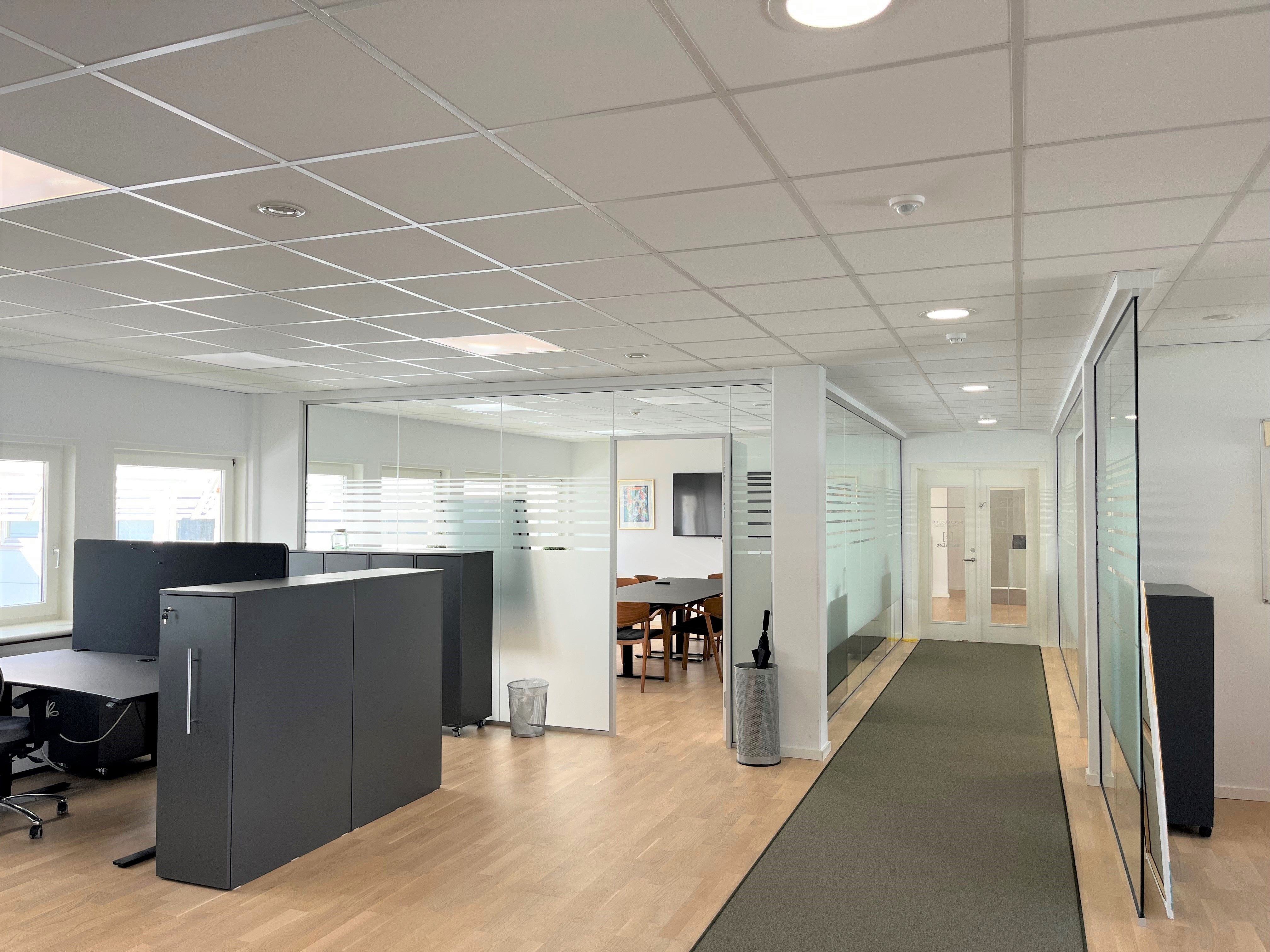 Moderne, minimalistisk kontor med glasskærme, møbler og lyse lofter, indretning med højkvalitetsmaterialer, slanke skuffer