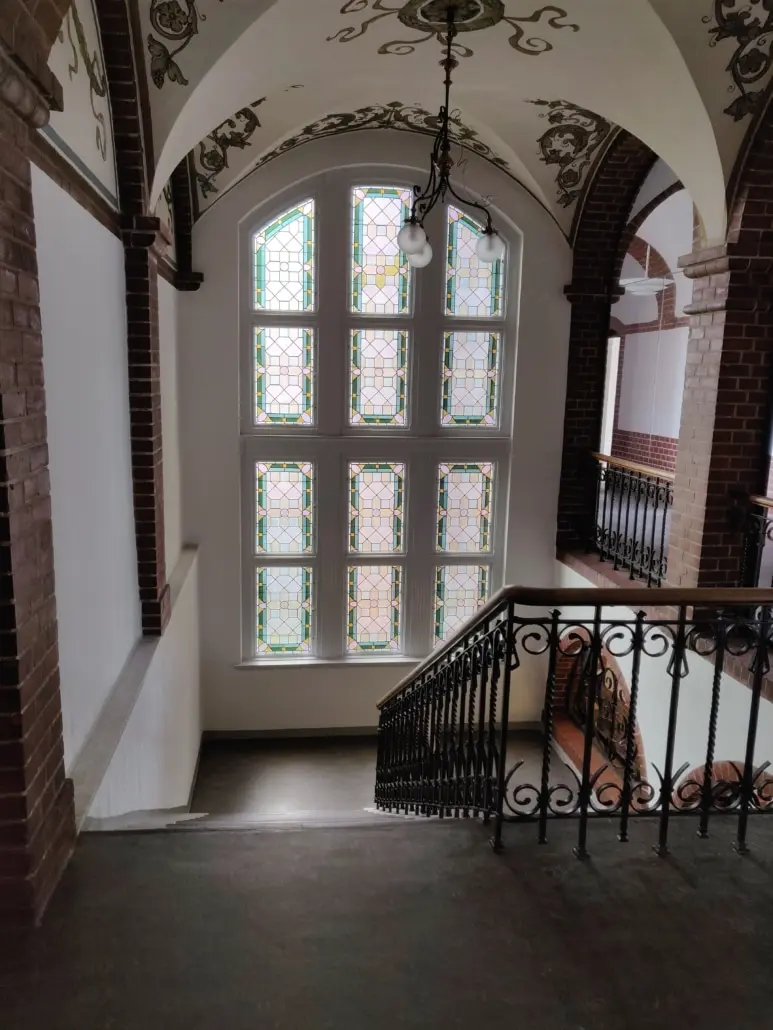 Indgangstrappet til Det Gamle Kredshus i Aabenraa Centrum med smukke, farvede glasruder og smedejernsgelater