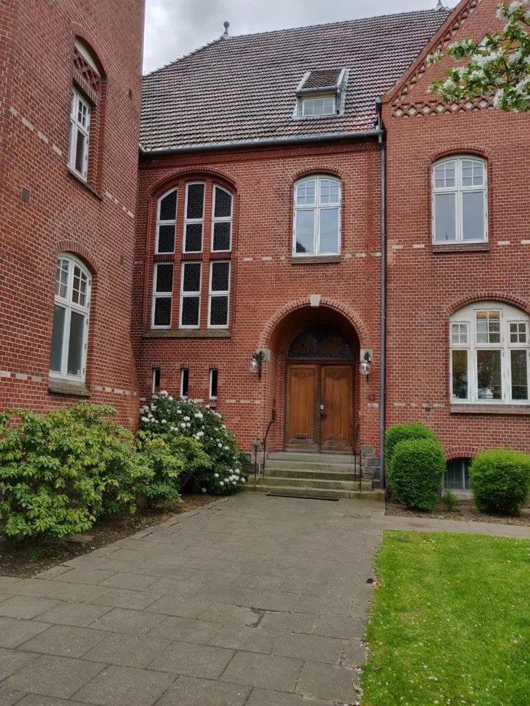 Det Gamle Kredshus er et rødt murstenshus med slanke vinduer og bjælkeloft. En stor trædør med to hængelampe på hver side og