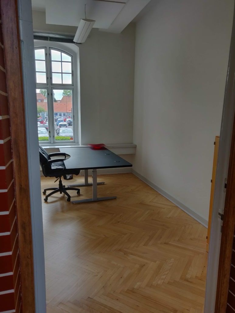 Et kontor med en bord, der er skråstillet, og en stol, der er placeret tæt ved bordet.