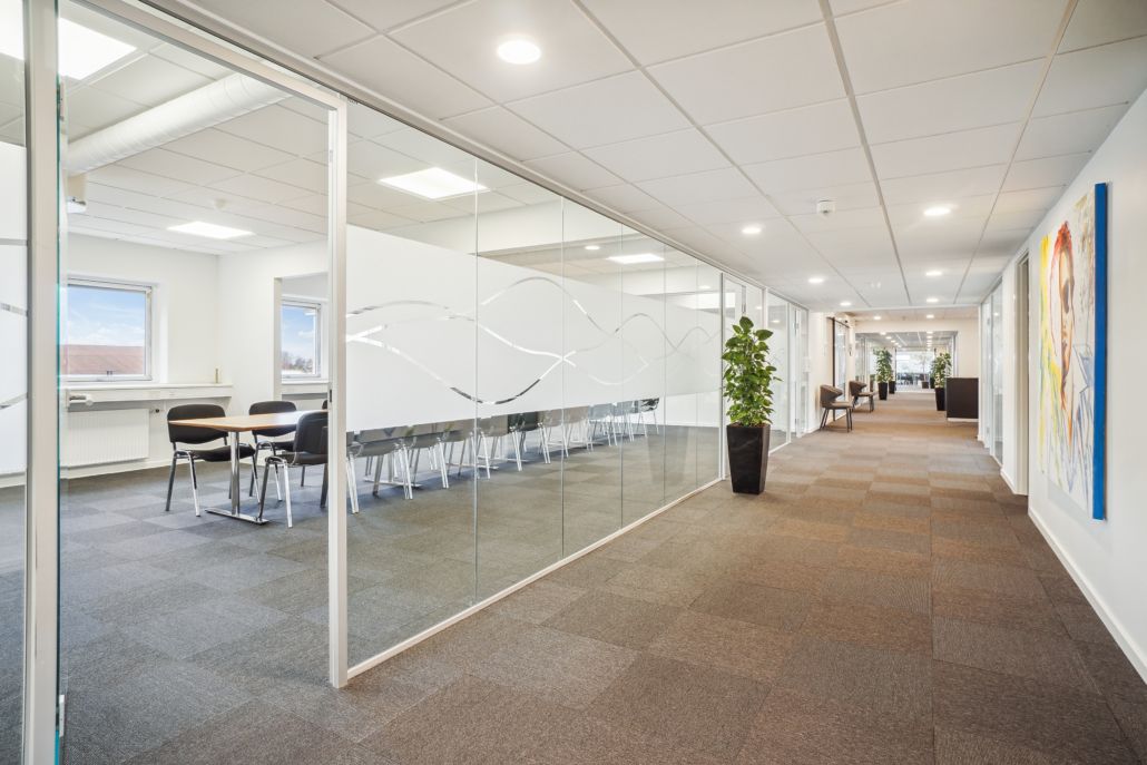 Glasmure og en enkelt bord med fire stole og et plante i gulvet