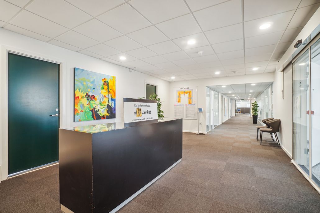 Møntørfællesskabets kontor med en sort reception, lyse lofter og en plante ved siden af to stole.