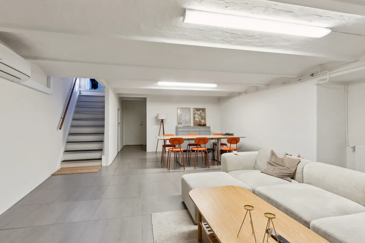 Stue med højt loft og lyse hvide vægge, moderne møbler, lyse og rummelige værelser med indbygget køleskab og lysekroner