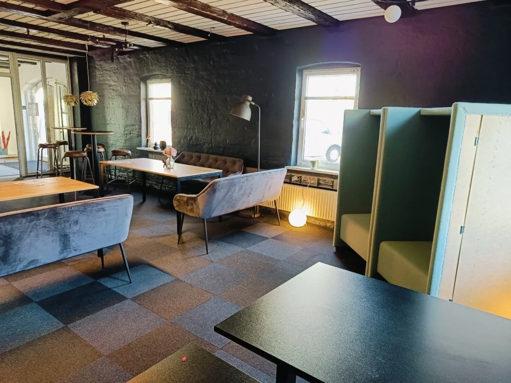 En hyggelig kontor med flere borde, stole, og en lysekron, alle med en sjov og hyggelig atmosfære