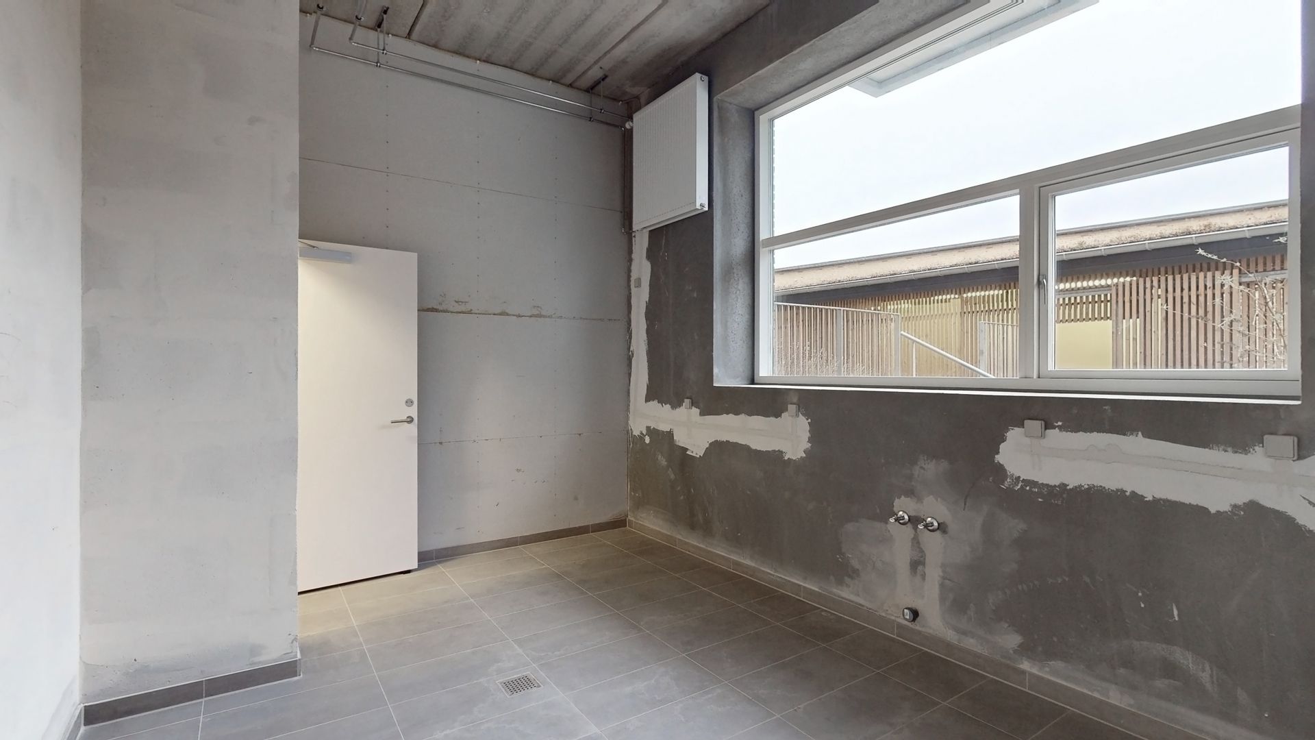 En tom stue med hvidt gulv og tørre vægge og stiger og trægulv i baggrunden