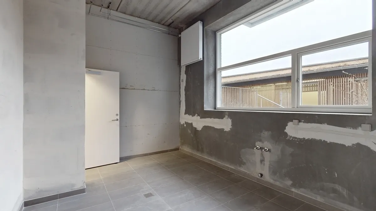 En tom stue med hvidt gulv og tørre vægge og stiger og trægulv i baggrunden