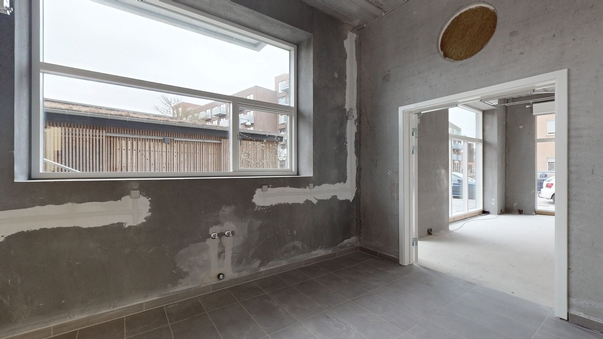 Store vinduer i renoveret lokale med hvid gulv og delvist malede vægge