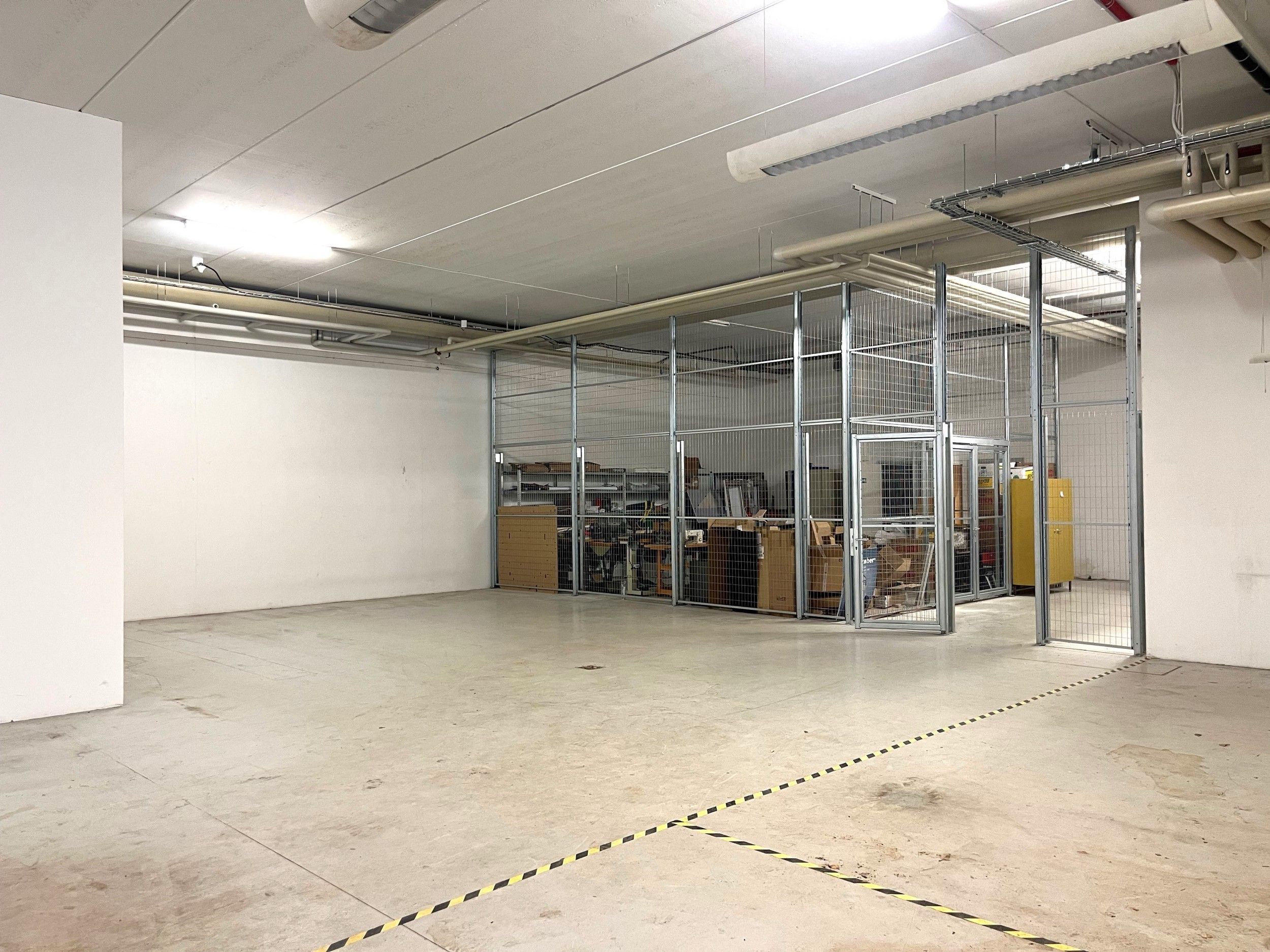 Lagerlokaler med højde til loftet på fire meter, to porte og indhegnet område med flere lagerhylder og varer