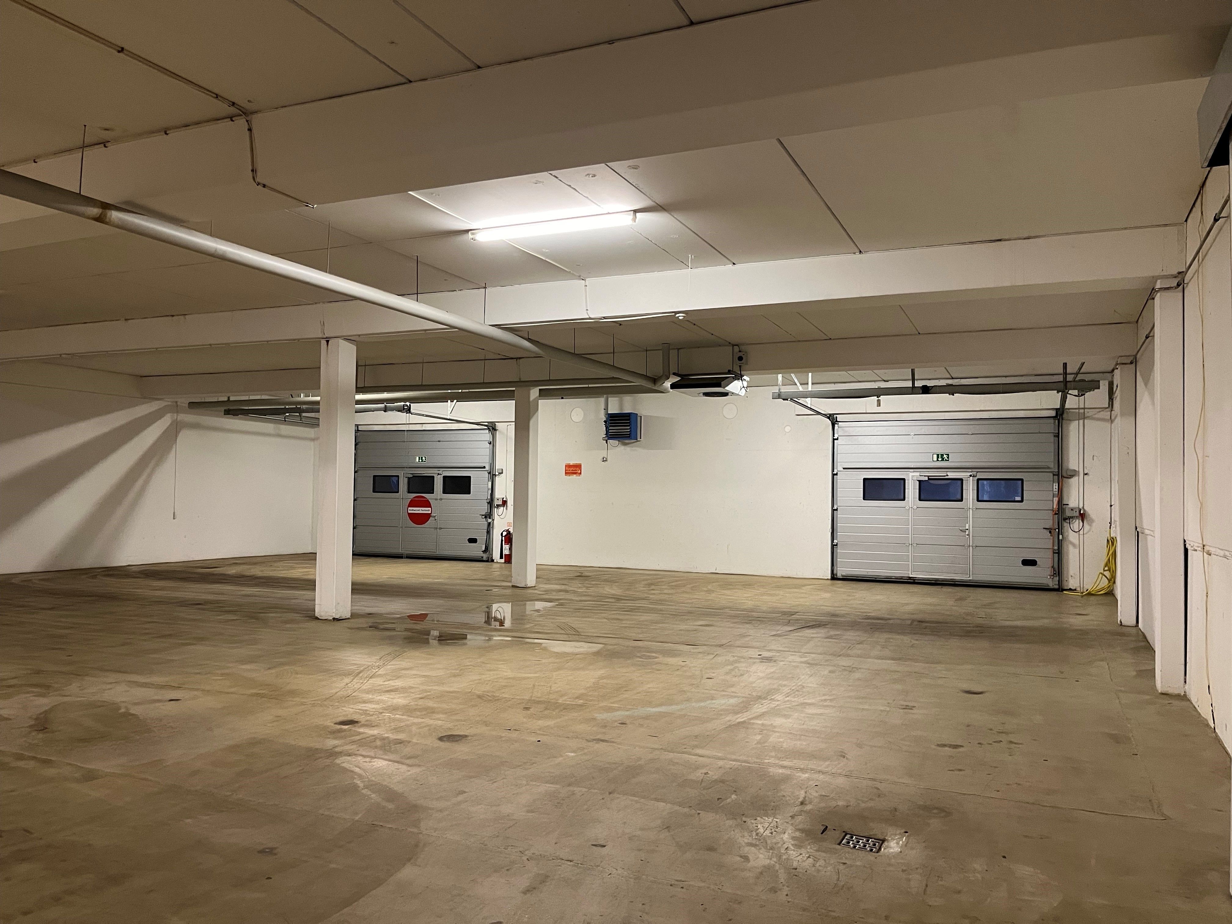 Lejemålet i underetagen har højt loft og lyse loftslamper, der giver god belysning, og der er to garageporte, der er lukkede