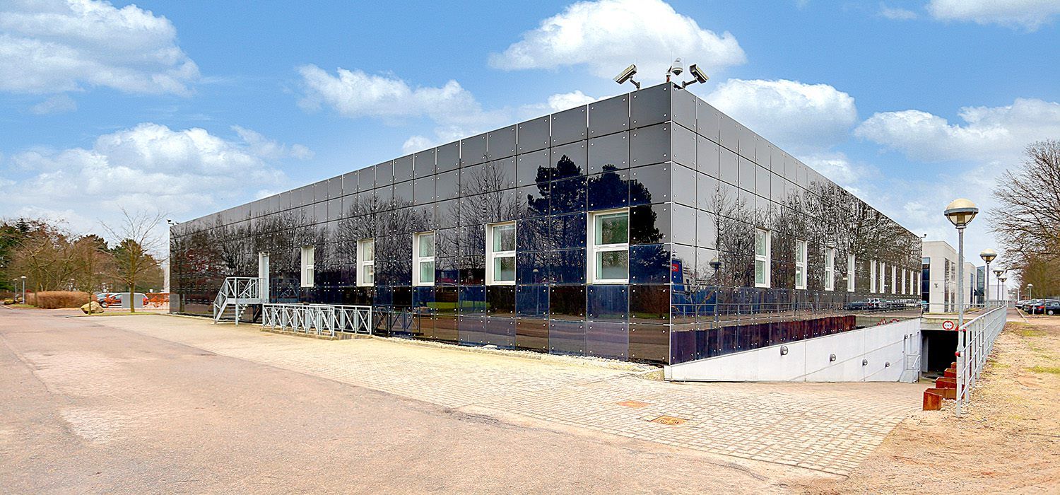 Lejemål med blanke vægge og vinduer og to porte i en parkeringsplads med mange biler parkeret