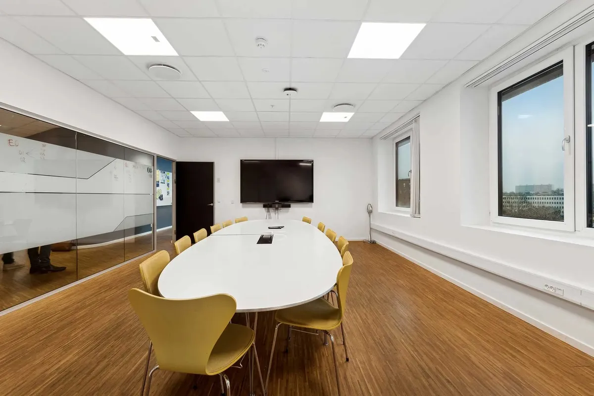 Elegant kontor med lyse gulve, runde bord og lysekroner i loftet samt skrivebordsvæg og vinduer