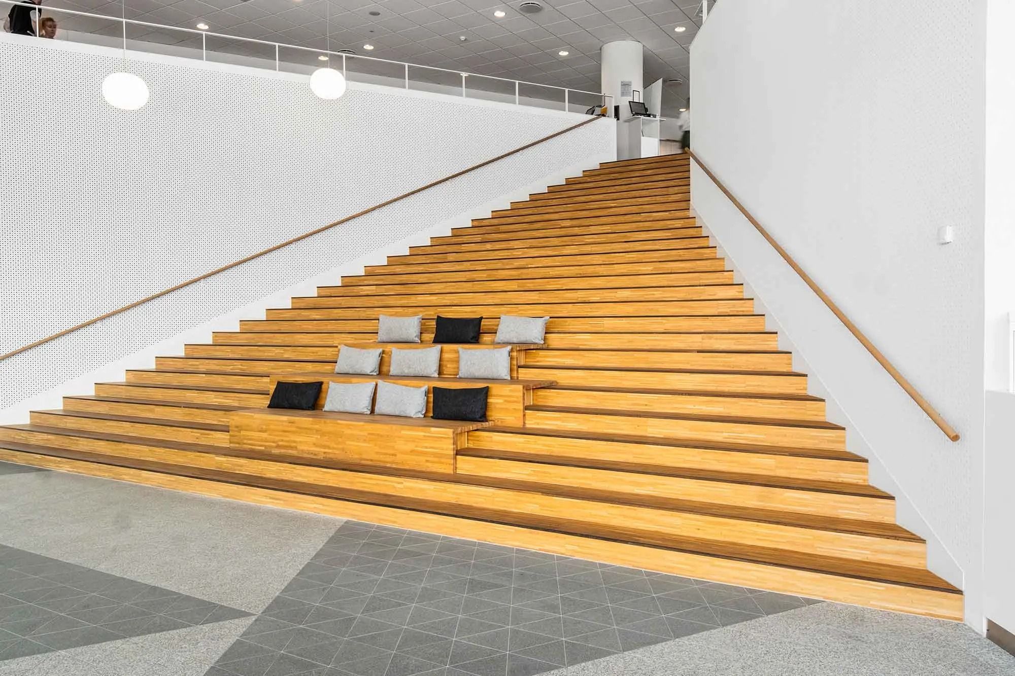 Elegant design med trætrapper og højt gulv uden skråning, indrettet med moderne højttaler og lysepunkter for brug i kontor.