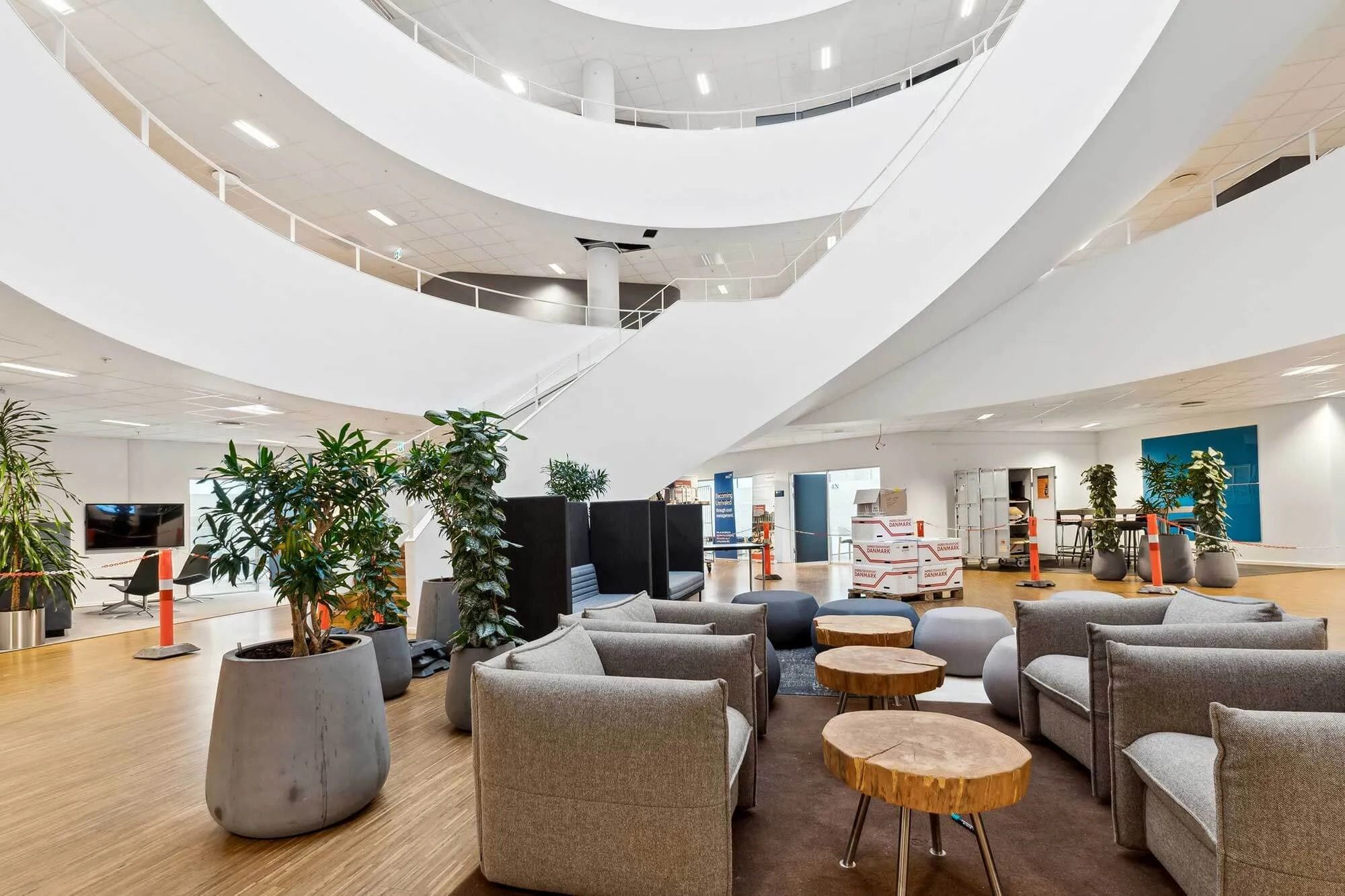 Moderne lobby med lyse gulve, høje hvide vægge, sofaer og bord, samt indvendige grønne planter