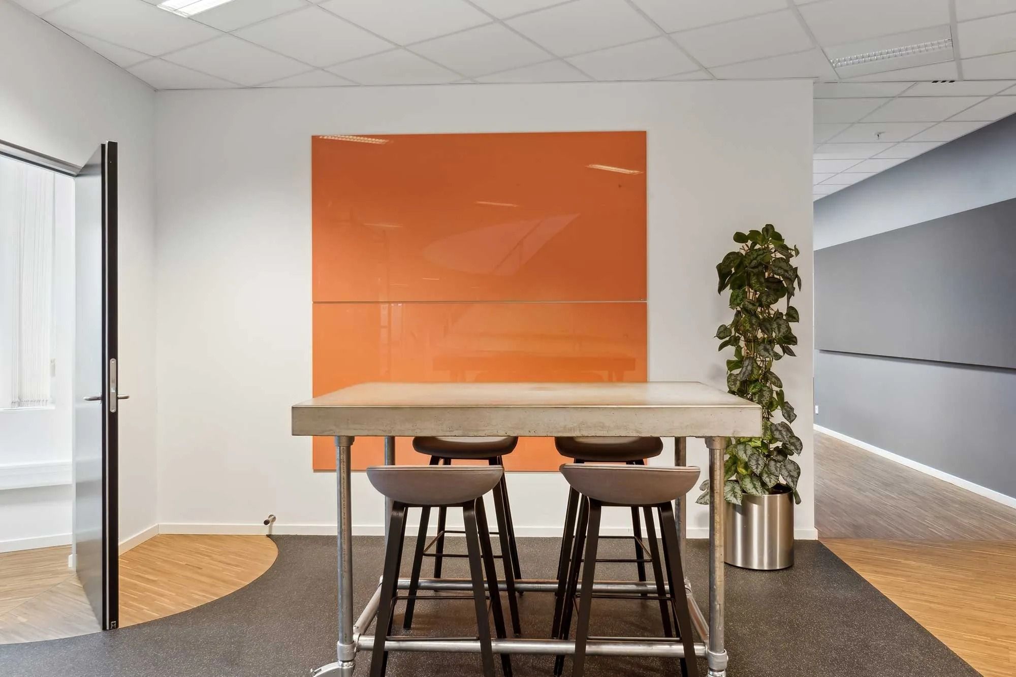 En stor mødesal med gulvbelægning og en stor orange væg, en stor plante og en stor gulvbelægning