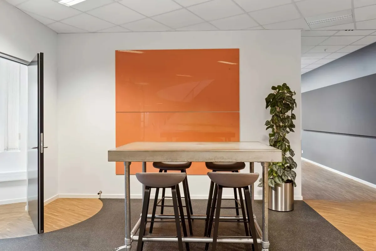 En stor mødesal med gulvbelægning og en stor orange væg, en stor plante og en stor gulvbelægning