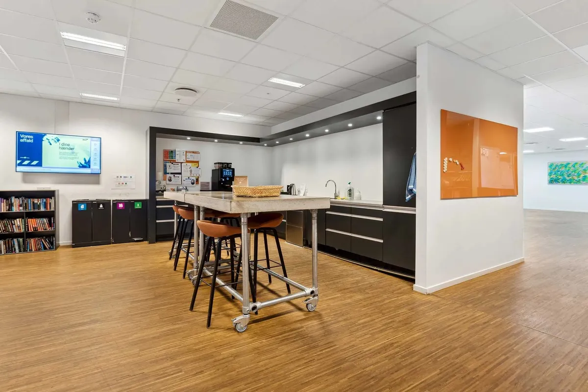 Moderne kontor med trægulv, højt loft, høj teknologi og bekvemmeligheder som en køkken og et bibliotek med bøger