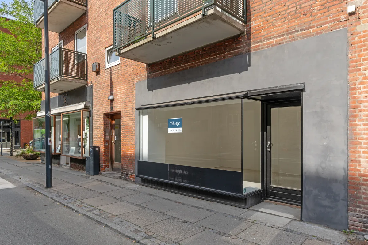 Butikslokal til leje på Ordrupvej 64 i Charlottenlund. Butikken med glasdøre og gulv i sort marmor. Balkon med gitter og et gulv i rustfrit stål.