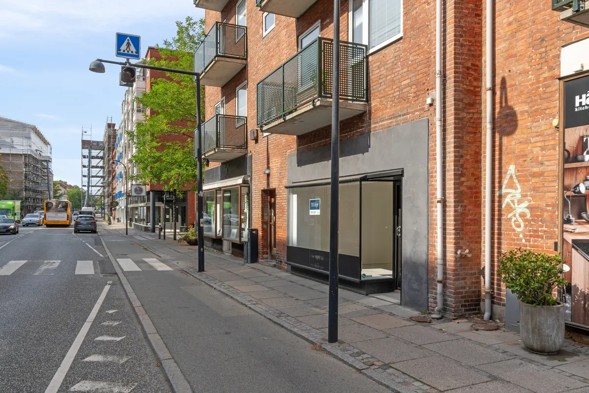 Butik til leje på Ordrupvej 64, Charlottenlund med kælder og praktisk lager. Et større lokale med udsigt til gågade og busser i baggrunden